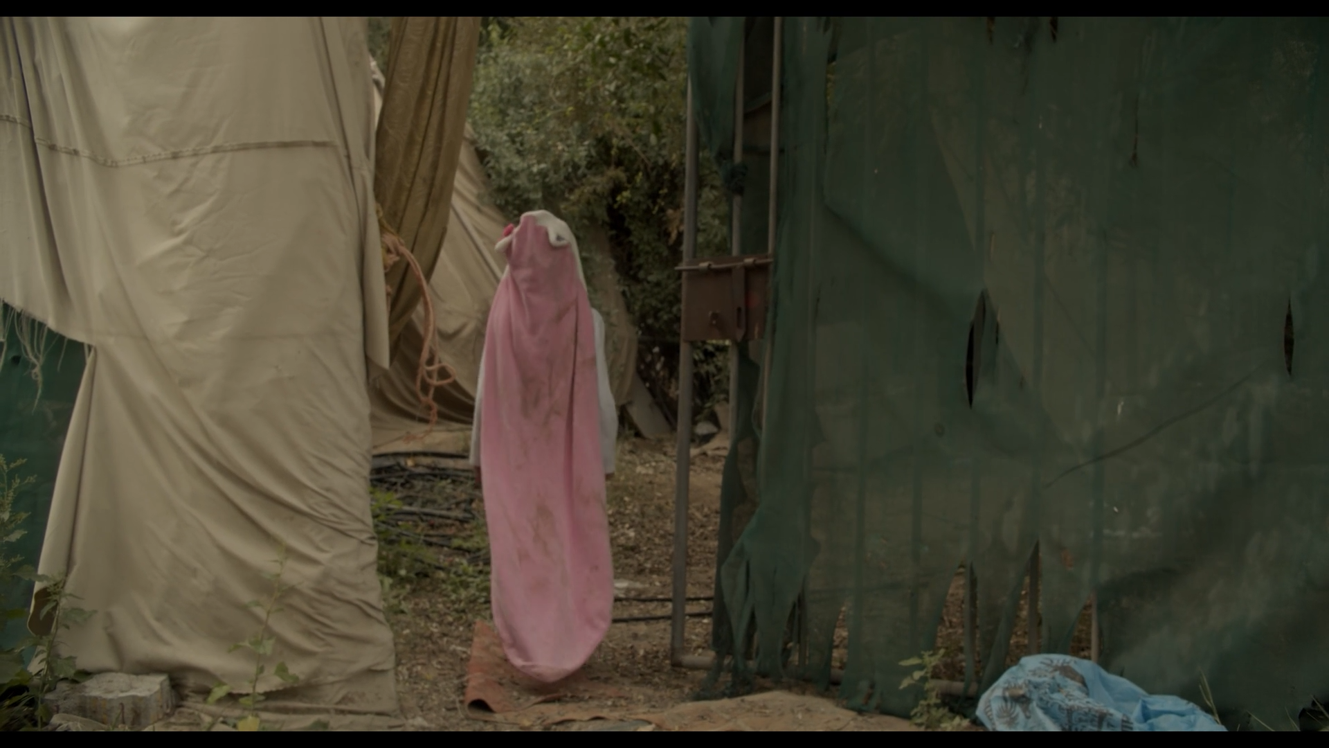 Woman with flowing pink fabric among hanging materials